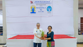 Director Prof Bhagwat is seen handing over a potted plant to the yoga instructor as a token of appreciation