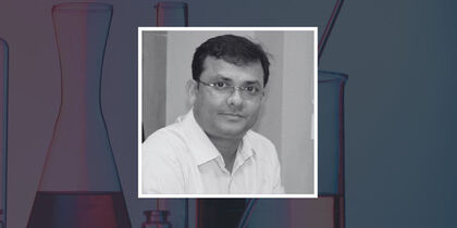 Prof. Sujit K. Ghosh's photo against a background representative of chemistry with flasks and measuring cylinders half-filled with liquids